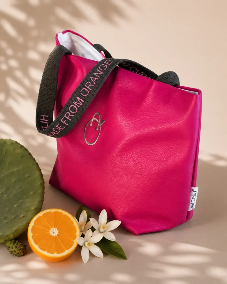 JOY tote bag by Vestella in Ohoskin Galatea, Pink Valentino vegan leather, with black handles embroidered Hi I am Made from Orange and Cactus, beside a cactus pad and half an orange